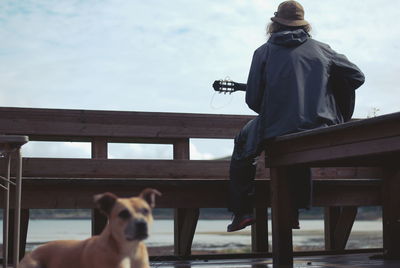 Dog by guitarist against sky