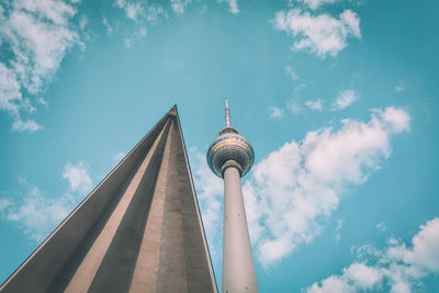 Low angle view of communications tower against cloudy sky