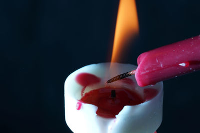 Close-up of hand holding ice cream cone against black background