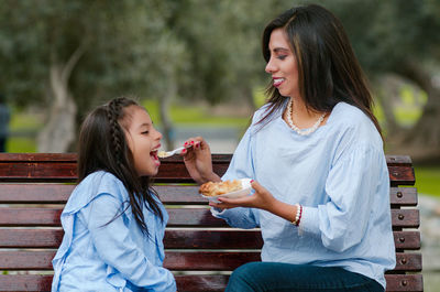 Young woman eating food on bench