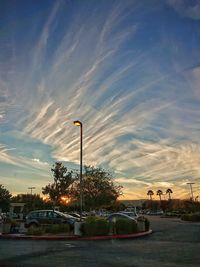 Cars on street against sky at sunset