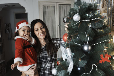 A mother and daughter decorate the christmas tree