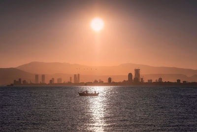 Scenic view of sea by silhouette mountains against sky during sunset