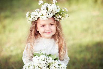 Portrait of cute girl holding flowers standing at park