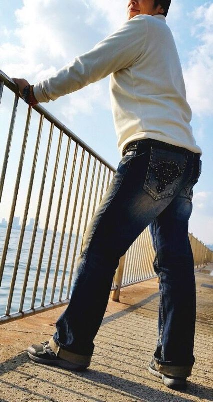 lifestyles, low section, casual clothing, standing, sky, leisure activity, person, full length, men, rear view, walking, shoe, jeans, cloud - sky, railing, day, outdoors