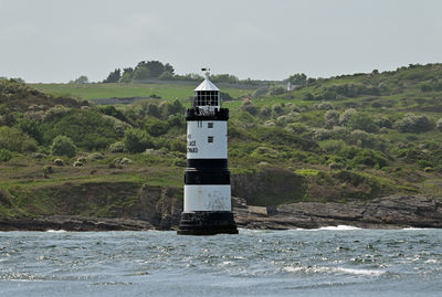 Lighthouse by sea against sky