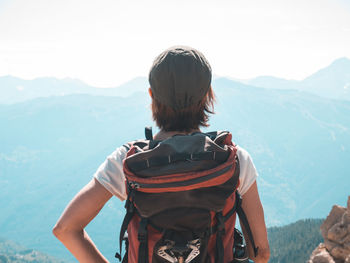 Rear view of man looking at mountains against sky