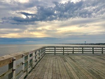 Pier over sea against sky during sunset