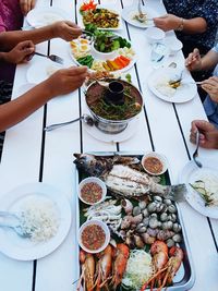 Cropped hands picking food from containers on table