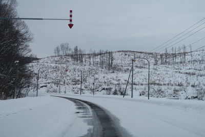 Road amidst snow covered trees against sky