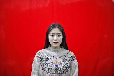 Portrait of woman standing against red wall