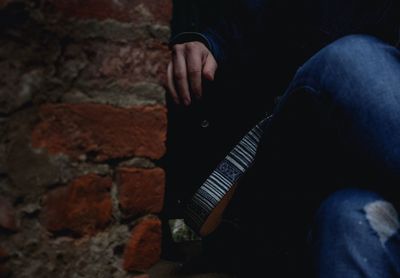 Low section of man sitting on wall