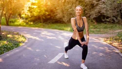 Full length of young woman sitting on road