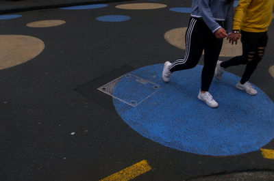Low section of people walking on road marking in city