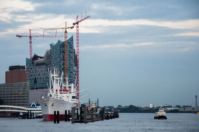 Cranes at commercial dock against sky