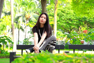 Portrait of young woman sitting in greenhouse