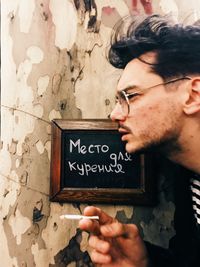 Side view portrait of young man holding text against wall