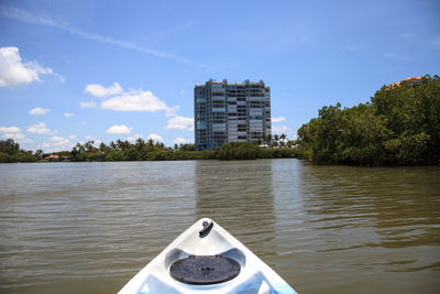 Buildings by river against sky