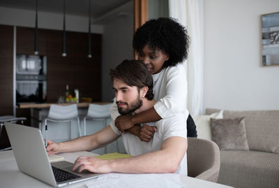 Black woman helping man with remote job