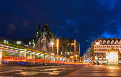 Light trails on street against buildings at night