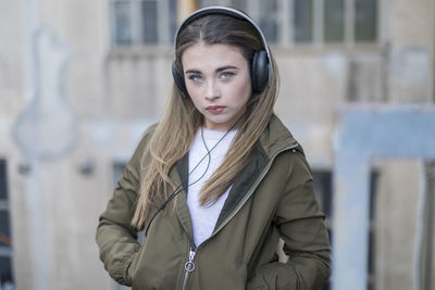 Portrait of teenage girl listening song while standing outdoors