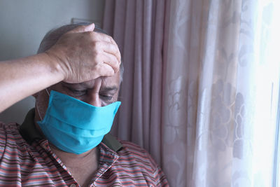 Senior man with face mask feeling sick .