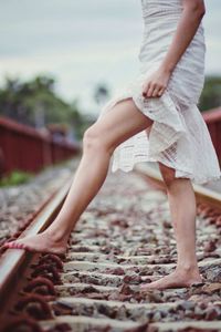 Low section of woman standing on railroad track