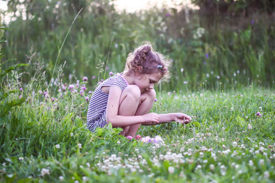 Cute girl crouching on grass at park