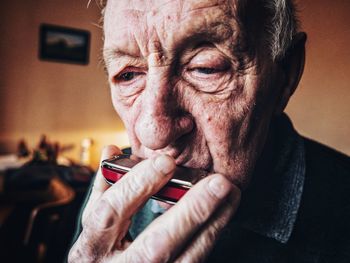 Close-up of senior man playing harmonica at home