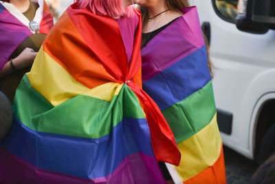 Woman wearing rainbow flag during parade in city