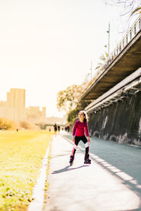 Cute girl wearing inline skate on footpath outdoors