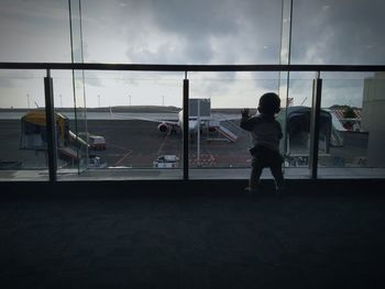 Rear view of people waiting at airport against sky