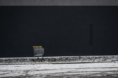 Shopping cart on street against black wall