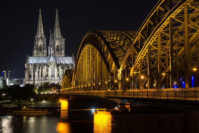 Hohenzollern bridge over river rhine against cologne cathedral at night