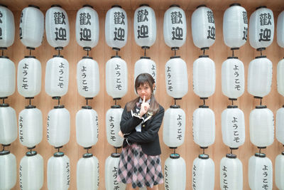 Portrait of teenage girl standing against lanterns