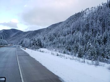 Road by snowcapped mountain against sky