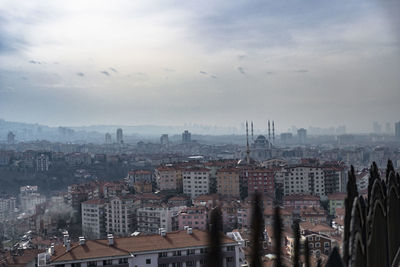 High angle view of city buildings against cloudy sky