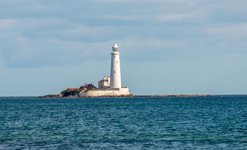 Lighthouse by sea against sky