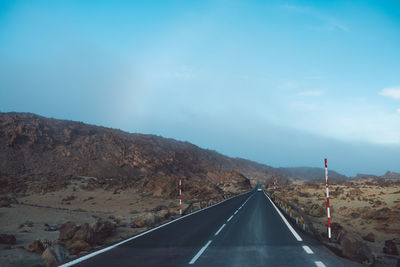 Road leading towards mountain against sky