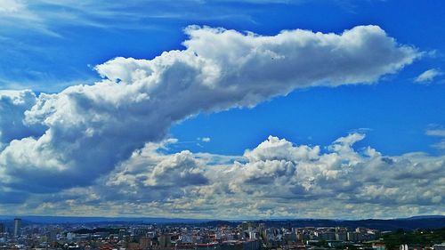 Aerial view of cityscape against cloudy sky