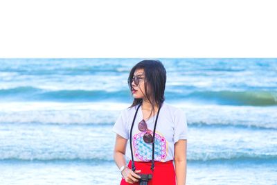 Woman standing on beach by sea against sky