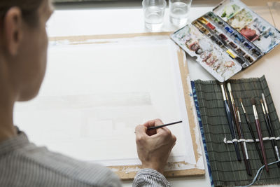 Cropped image of woman painting on canvas at table in creative office