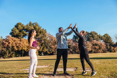 Full length of friends exercising together on field in public park