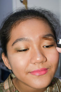 Portrait of a young girl getting make up applied to her face 