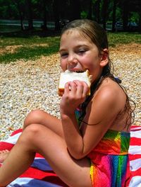 Portrait of girl eating food while sitting on beach