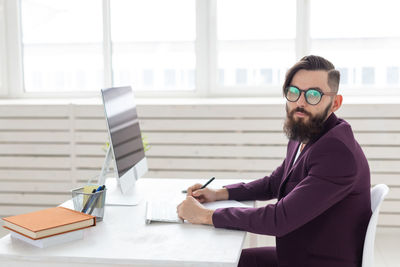 Young man using phone while sitting on table