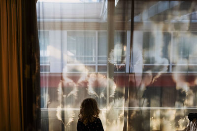 Rear view of woman looking through window