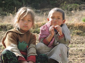 Portrait of siblings sitting on field