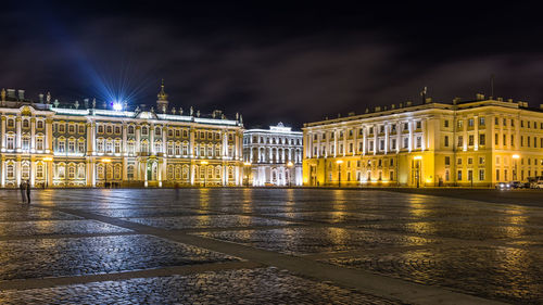 Illuminated building by street against sky at night