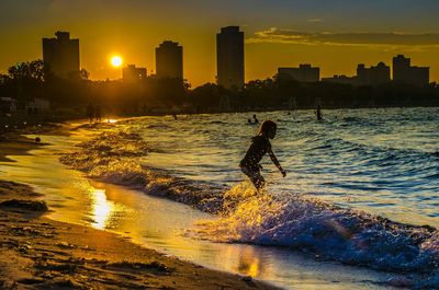 Silhouette man by sea against sky during sunset